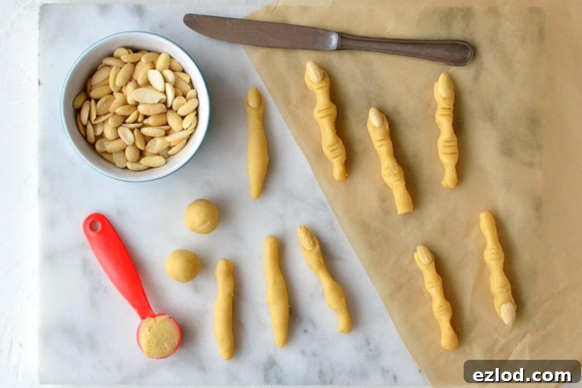 Witches' finger cookies being shaped with blanched almonds for nails and knife indentations for knuckles.