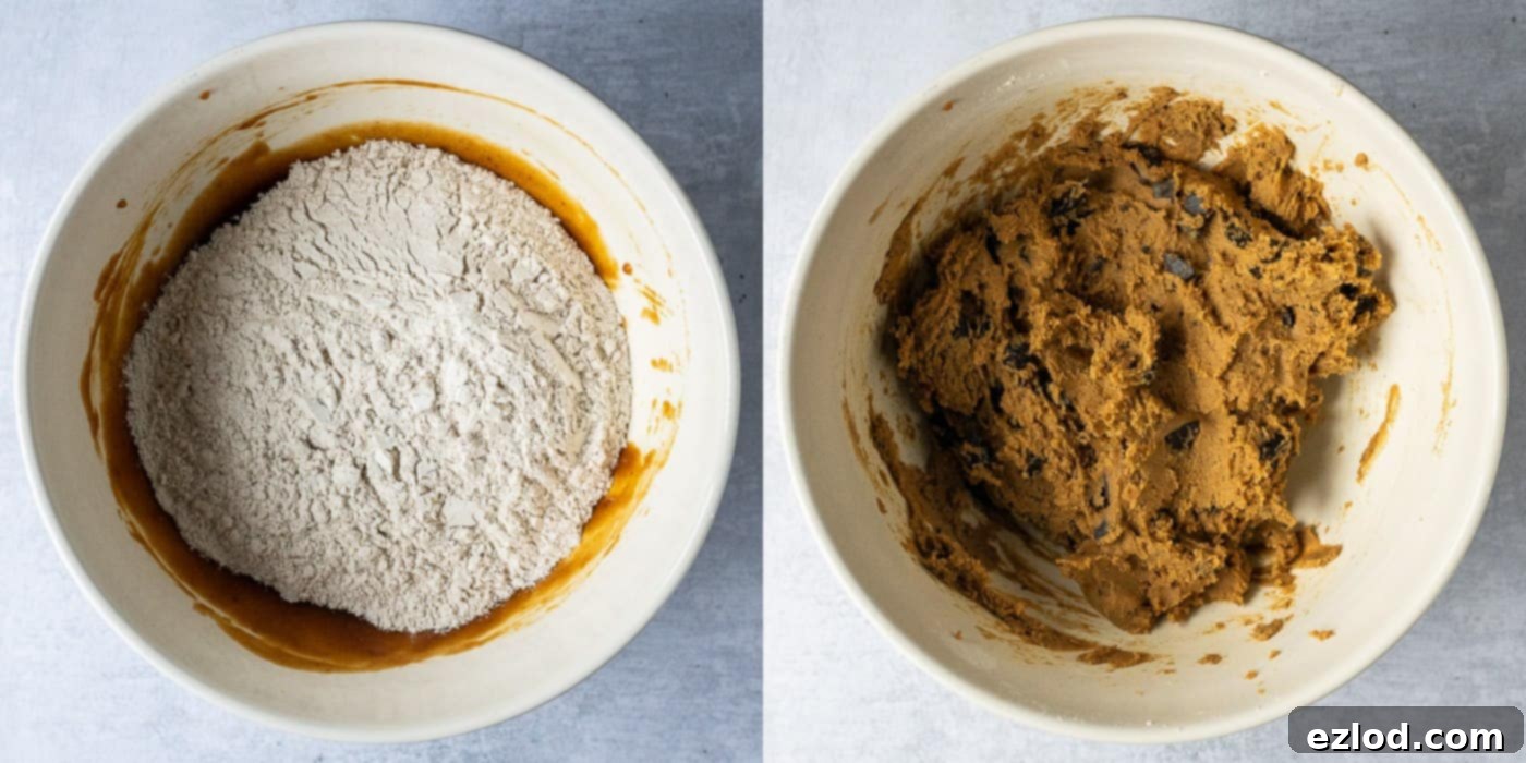 Step 3 in making vegan pumpkin chocolate chip cookies: The cookie dough is being mixed in a bowl with a spatula after the dry ingredients have been added to the wet. The dough is thick and appears to have chocolate chips folded in.