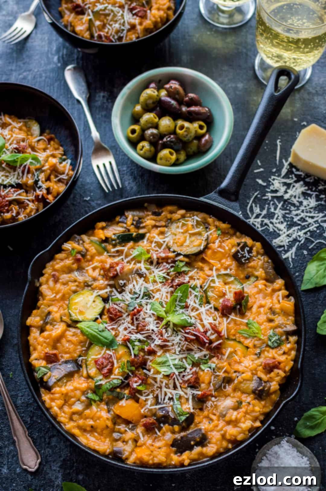 Angled shot of vegetarian ratatouille risotto served in a cast iron skillet with olives