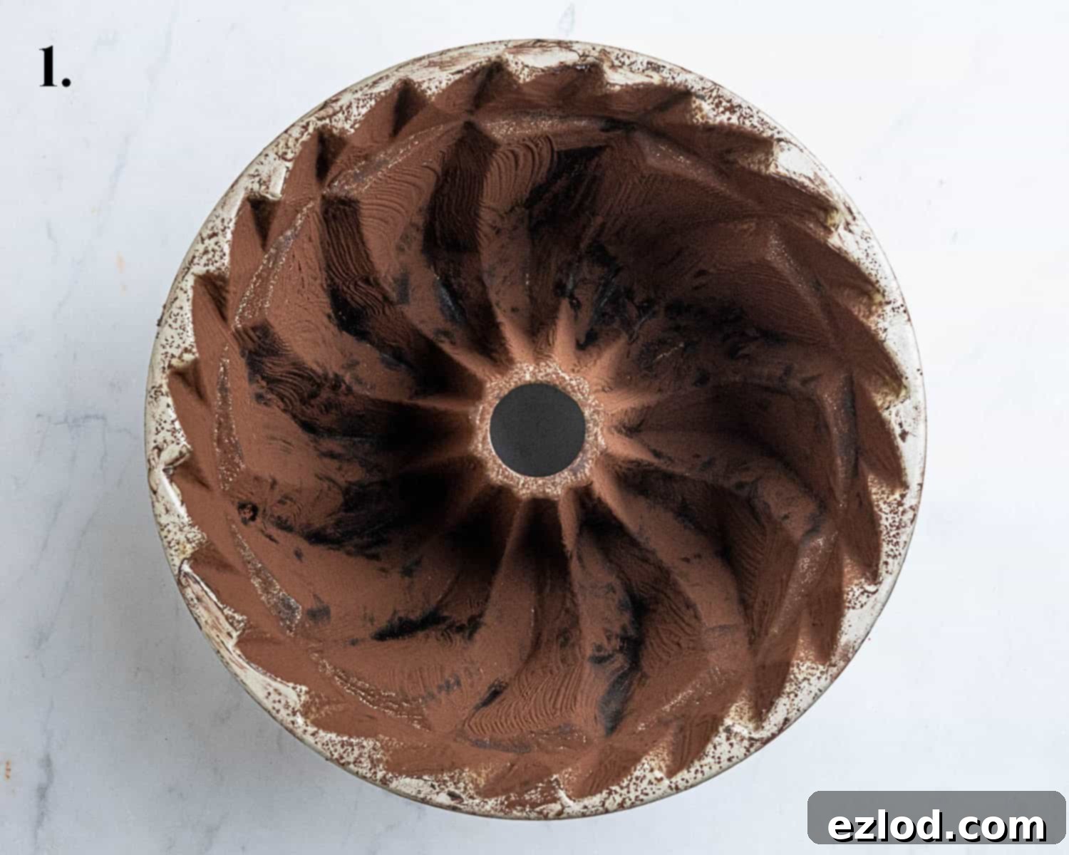 Decadent Vegan Chocolate Bundt Cake 5 Step 1 in making vegan chocolate bundt cake, showing a meticulously prepared bundt tin, brushed with melted vegan butter and dusted with cocoa powder.
