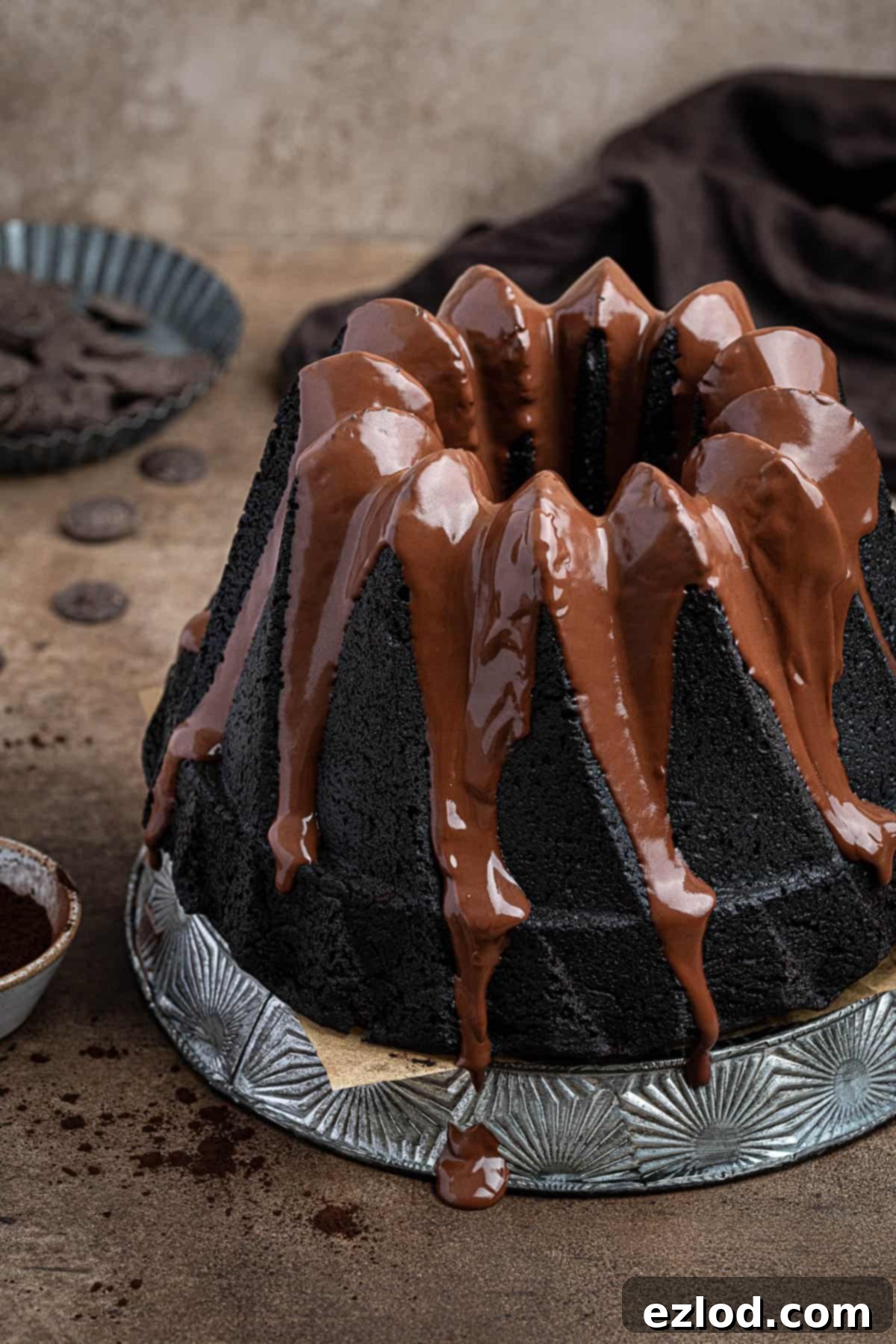 Decadent Vegan Chocolate Bundt Cake 10 A close-up shot of a perfectly baked vegan chocolate bundt cake sitting on a decorative metal plate on a rustic brown surface, showcasing its intricate design.