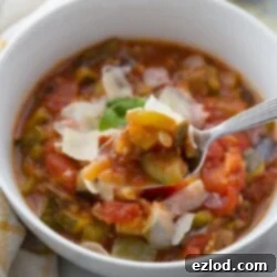 White bowl with warm Instant Pot Ratatouille, topped with parmesan and fresh basil
