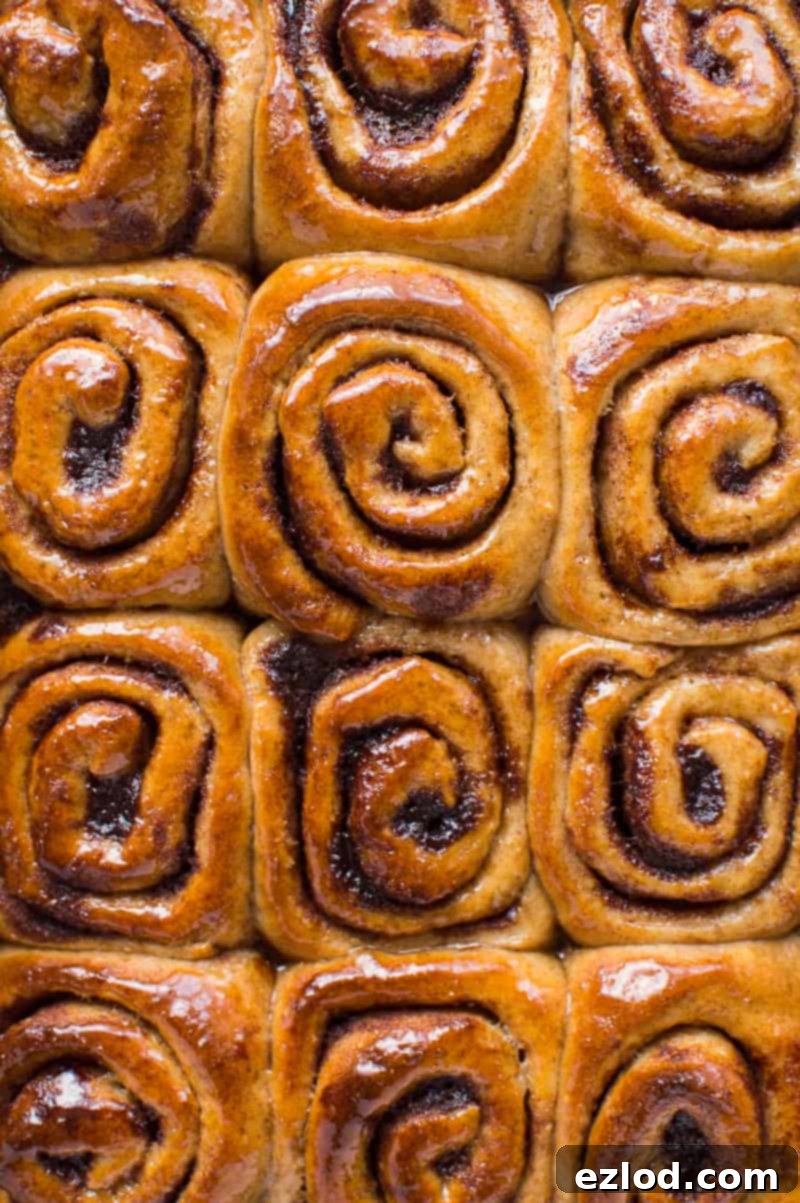 A vibrant top-down shot of freshly glazed vegan wholemeal cinnamon buns, showcasing their glossy finish and inviting texture, perfect for sharing on social media.