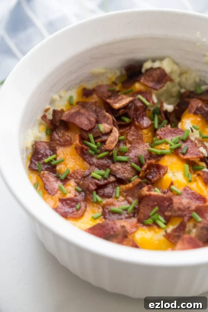 A white Instant Pot safe casserole dish topped with bacon, cheddar, and chives. 