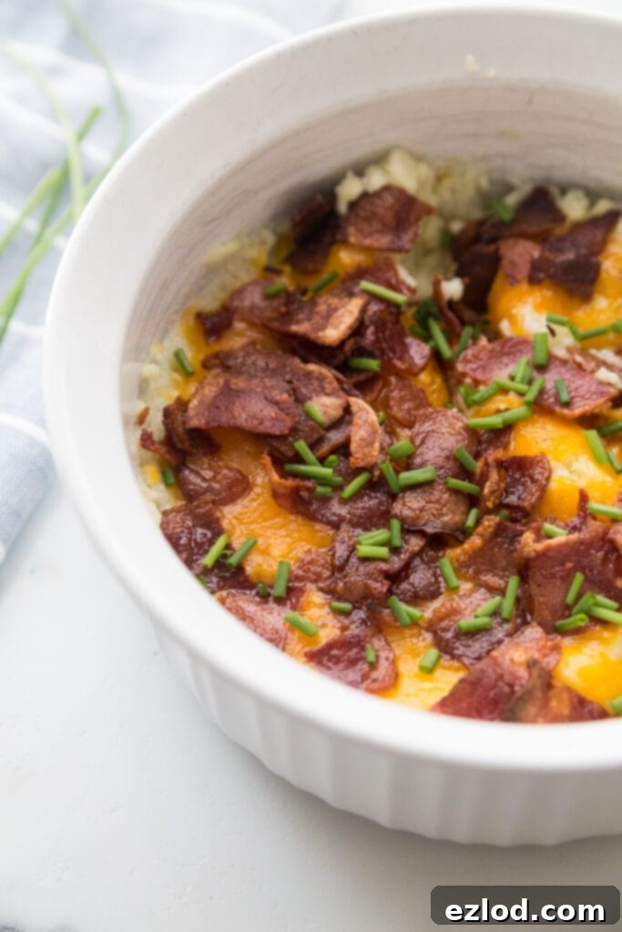 A white Instant Pot safe casserole dish with Mashed Cauliflower topped with bacon, cheddar, and chives. 