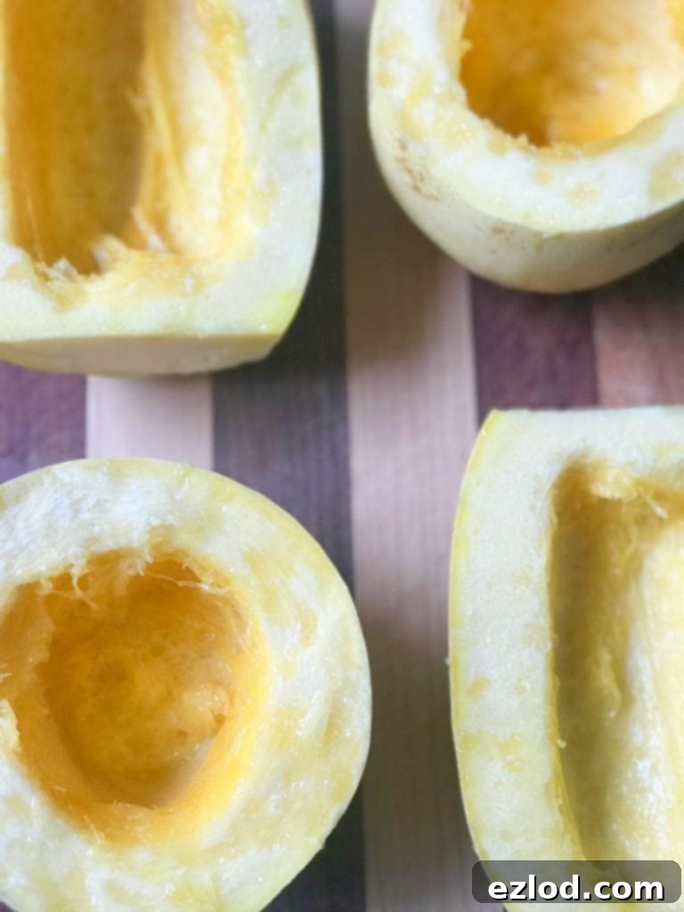 Four raw spaghetti squash halves, expertly sliced and arranged on a cutting board, ready for oven roasting.