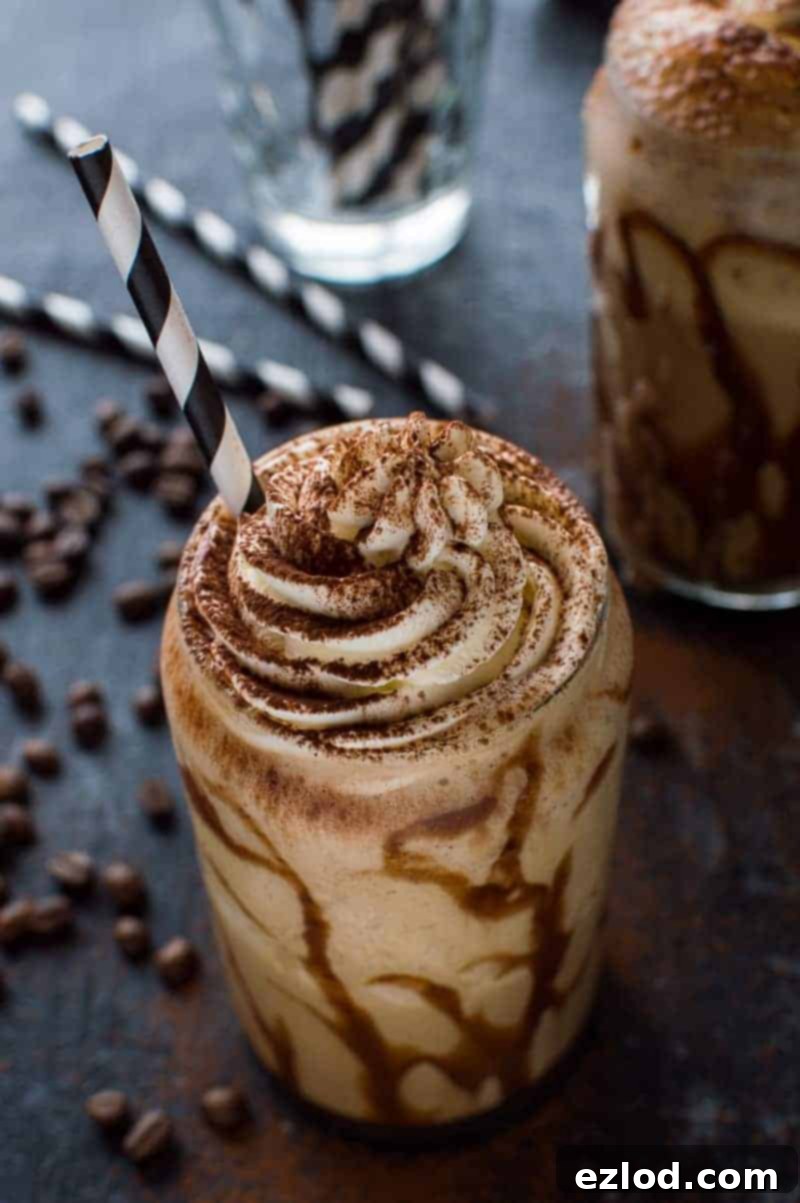 Two glasses of creamy boozy coffee milkshakes topped with whipped cream and chocolate drizzle on a dark background.