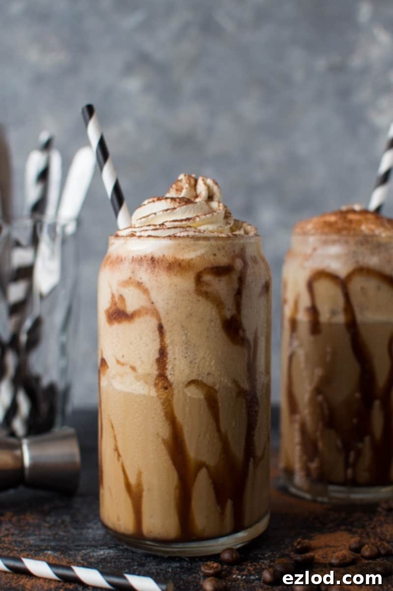Photo of two glasses of coffee Kahlua milkshakes with chocolate sauce, whipped cream and paper straws on a dark background, highlighting the rich texture.