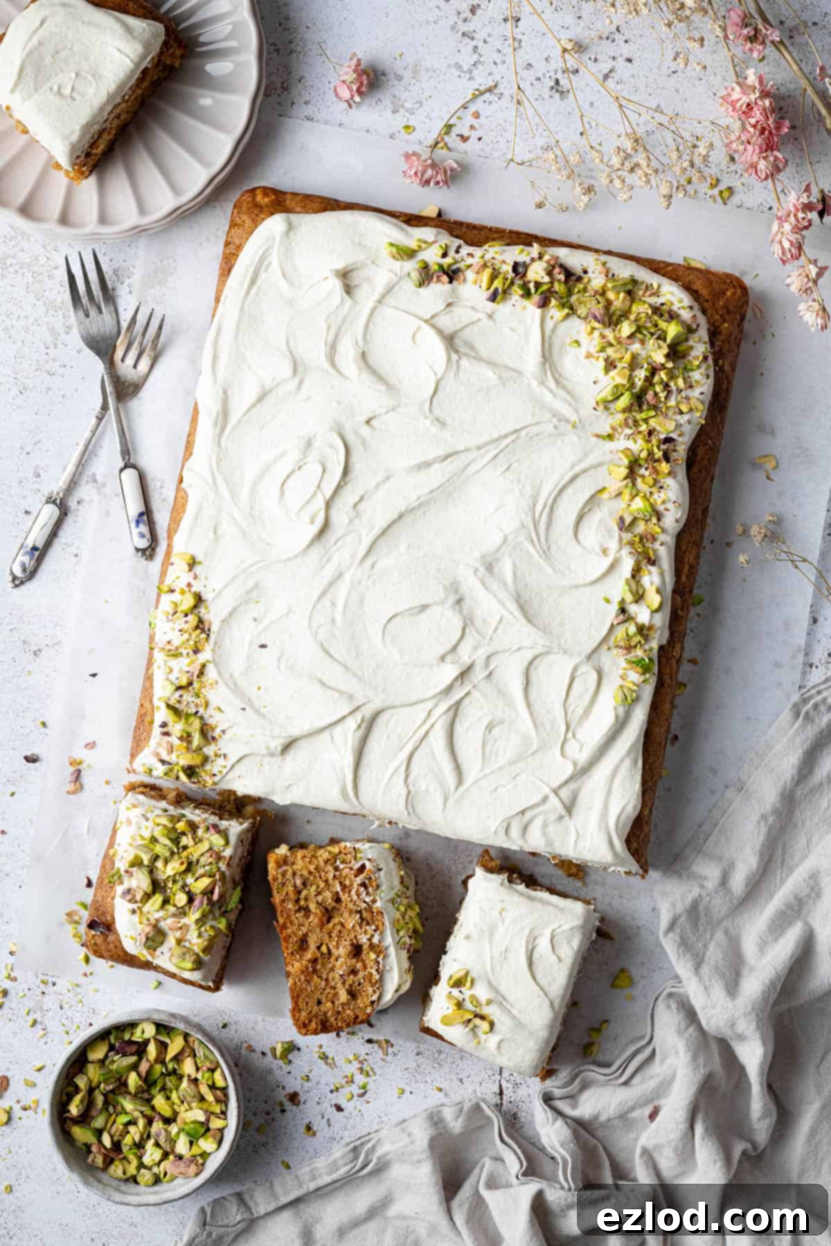 Vegan carrot, pineapple and pistachio cake with three slices cut, revealing its moist texture and vibrant inclusions.