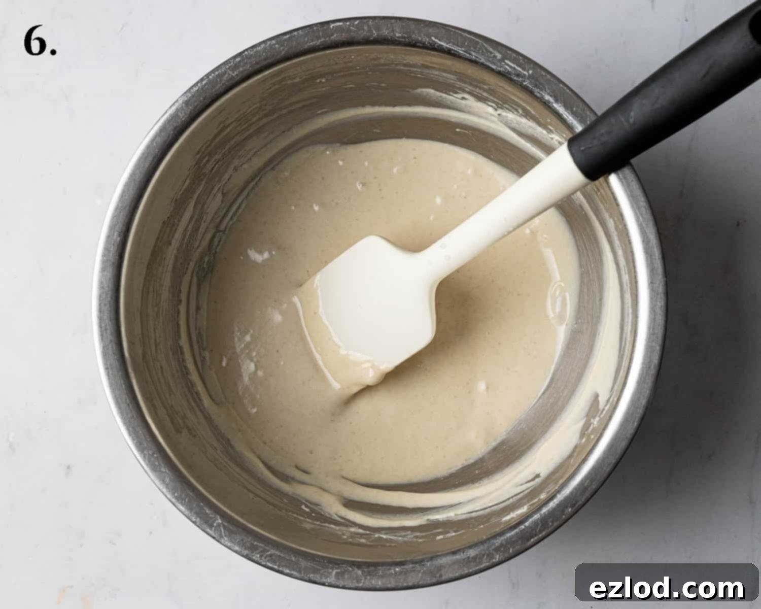 Step 6: Melted white chocolate being stirred into room temperature vegan cream cheese.