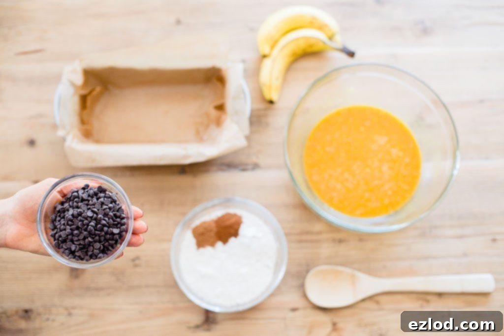 A flatlay of the ingredients to make Pumpkin Oatmeal Banana Bread on a light wood table. 