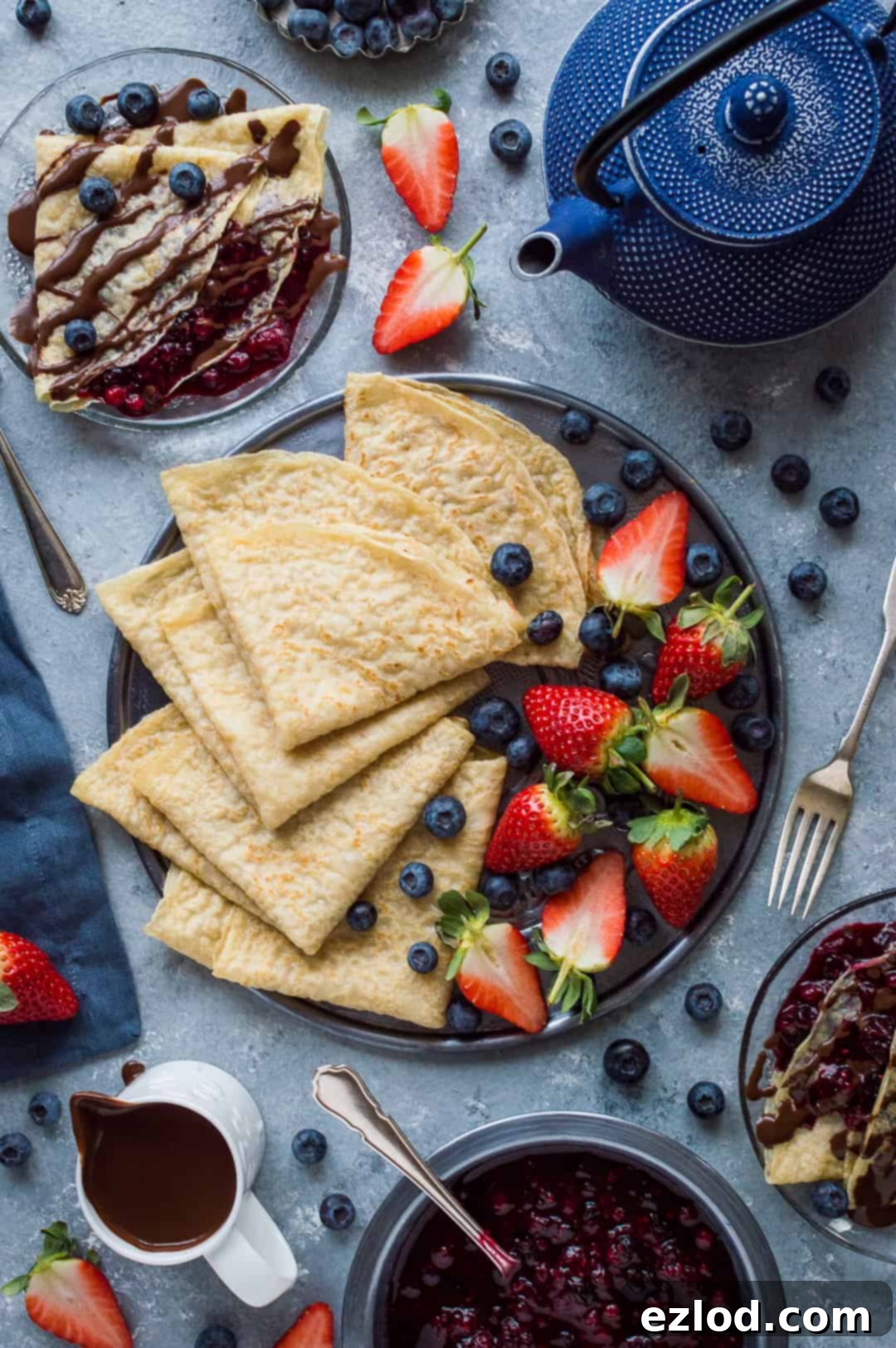 Top down shot of a breakfast spread of vegan pancakes with berries, chocolate sauce and berry compote.