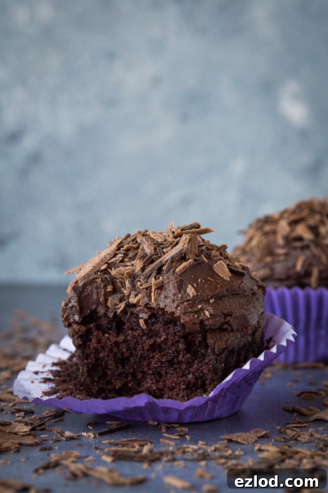 A close-up shot of a vegan chocolate cupcake with a bite taken out, revealing its moist and tender interior.