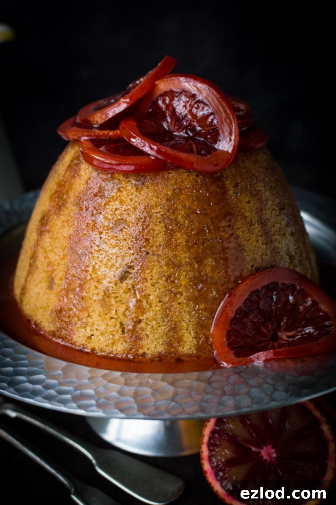 Close-up view of a homemade Crock-Pot steamed blood orange and ginger pudding, generously garnished with glistening candied blood orange slices.