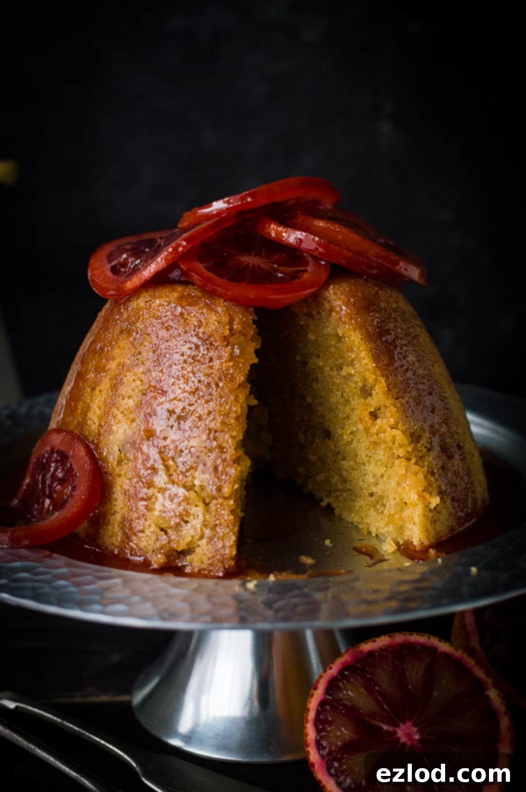 Intimate close-up of a perfectly sliced slow cooker blood orange and ginger steamed pudding, revealing its moist texture and vibrant color.