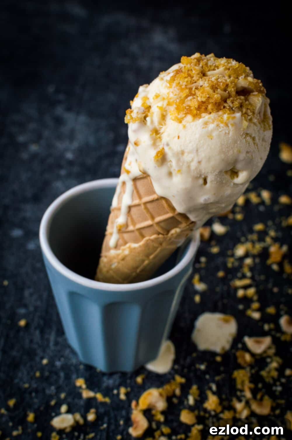 Vanilla hazelnut caramel praline ice cream in a cone on a black background.