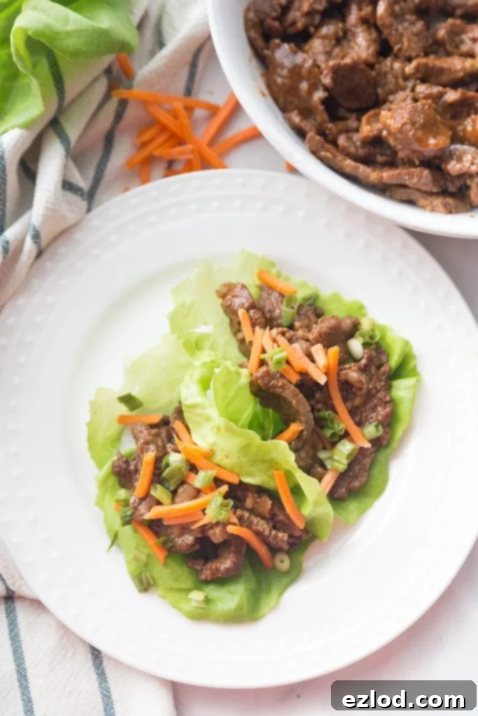 Tender Asian Steak Lettuce Wraps Instant Pot and Slow Cooker 2 White plate with Asian steak lettuce wraps topped with matchstick carrots.