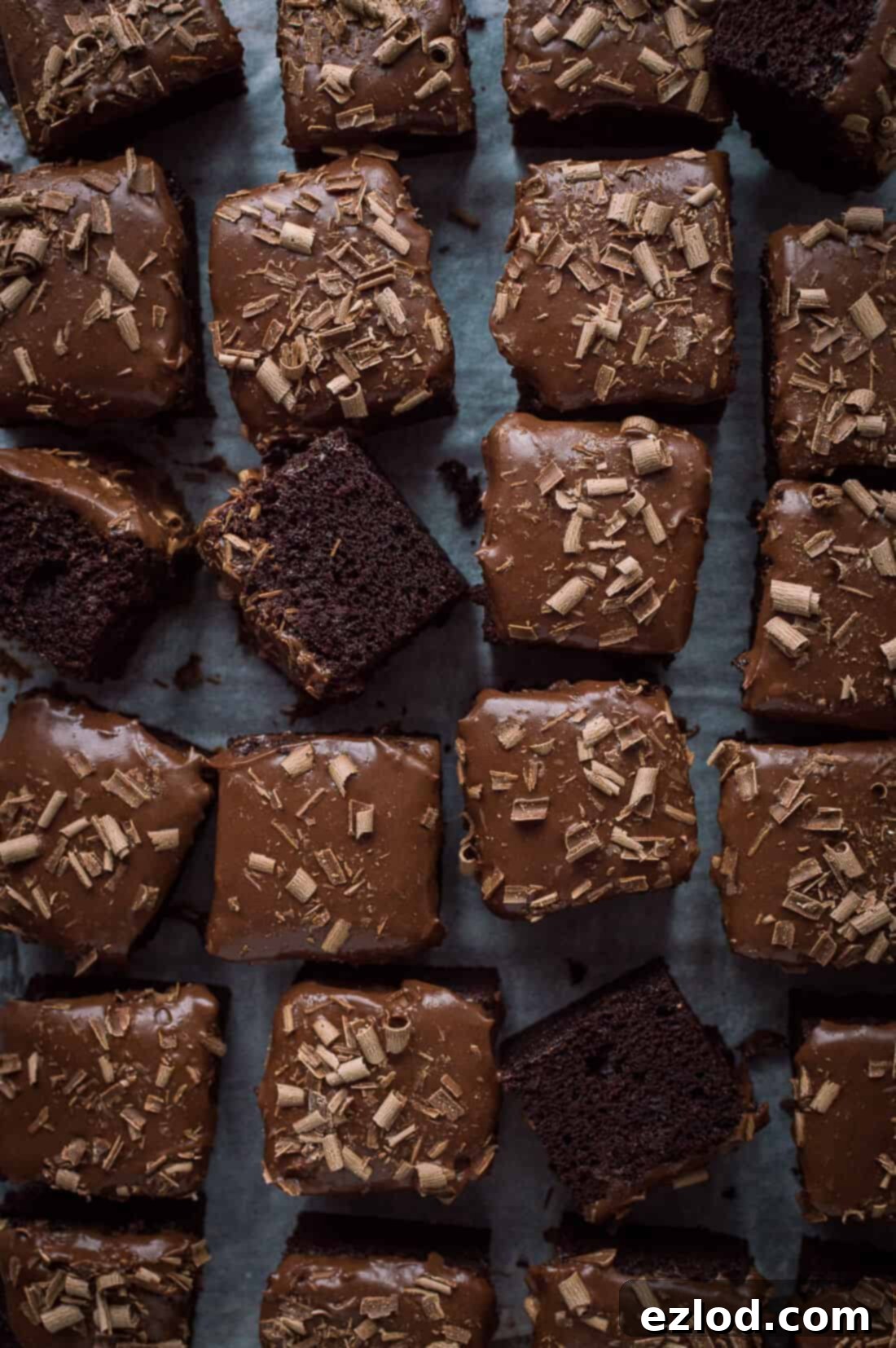 top down shot of vegan chocolate sheet cake sliced into squares and topped with chocolate ganache and chocolate curls.