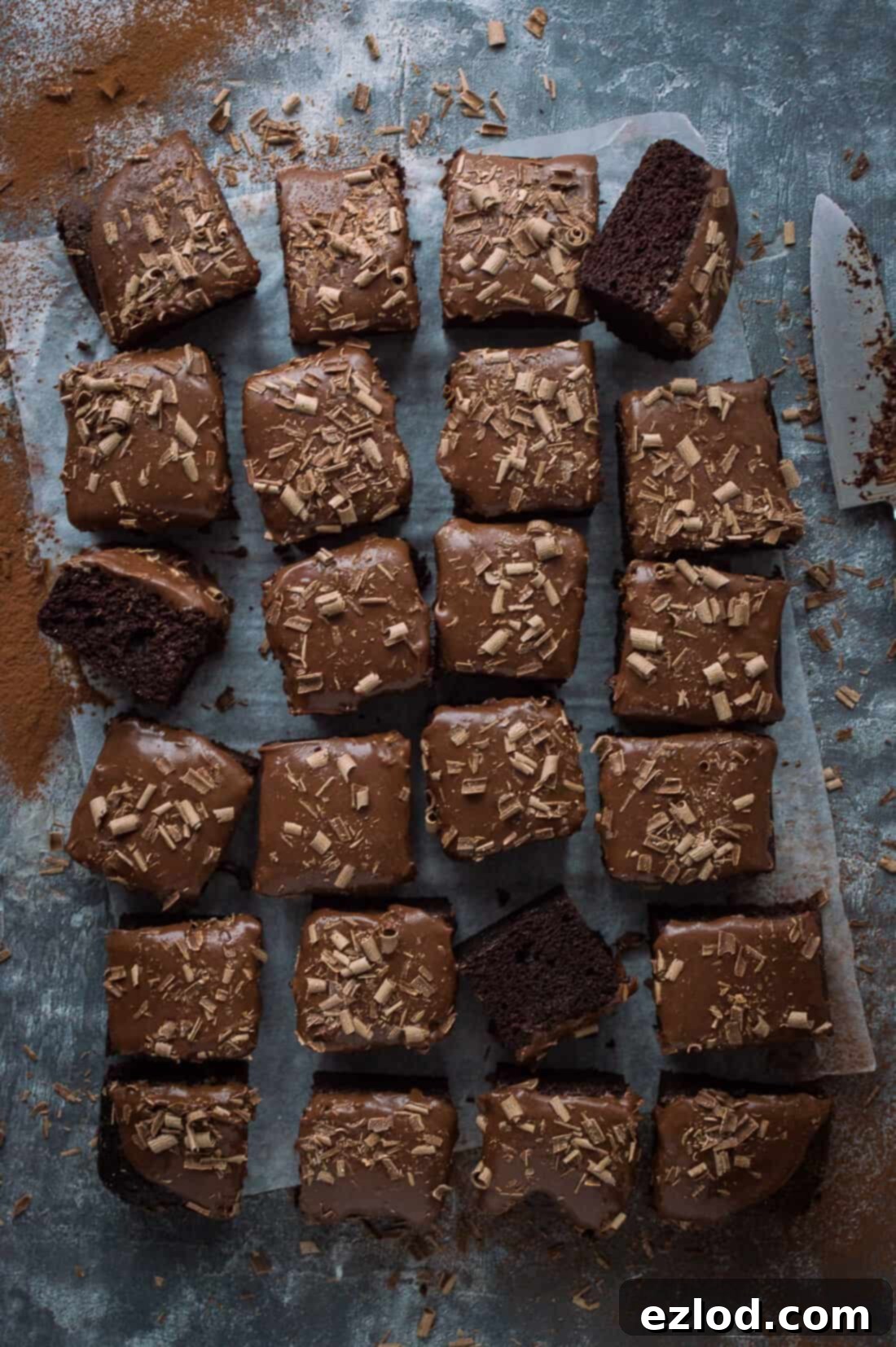 Vegan chocolate sheet cake with coconut milk ganache and chocolate curls sliced into squares.