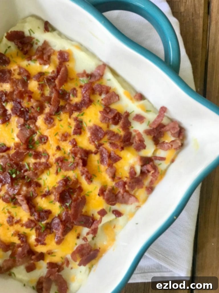 A square baking dish with mashed cauliflower topped with bacon, cheese, and chives - Instant Pot Loaded Cauliflower Mash