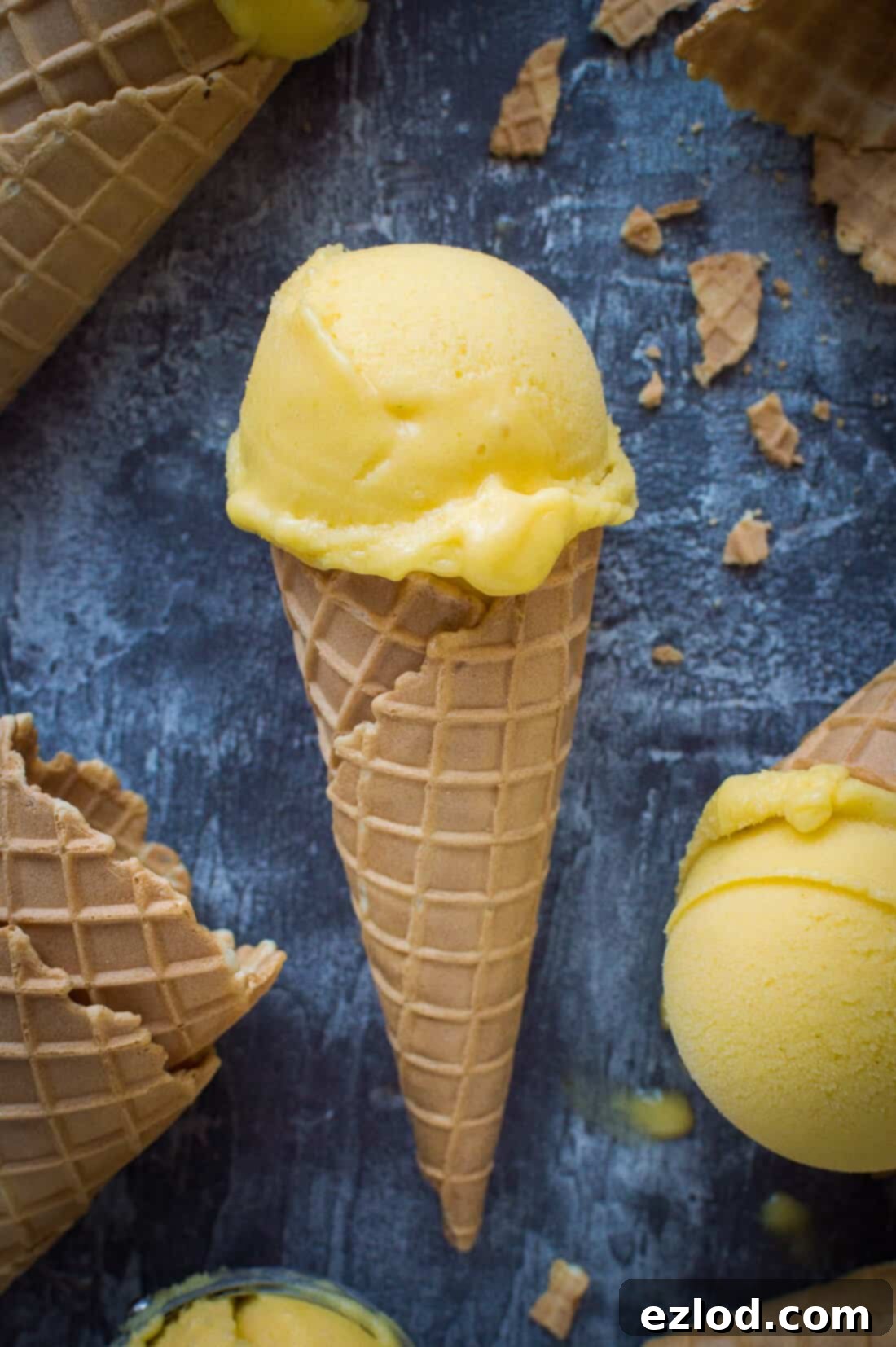 A scoop of vegan mango lassi sorbet in a waffle cone
