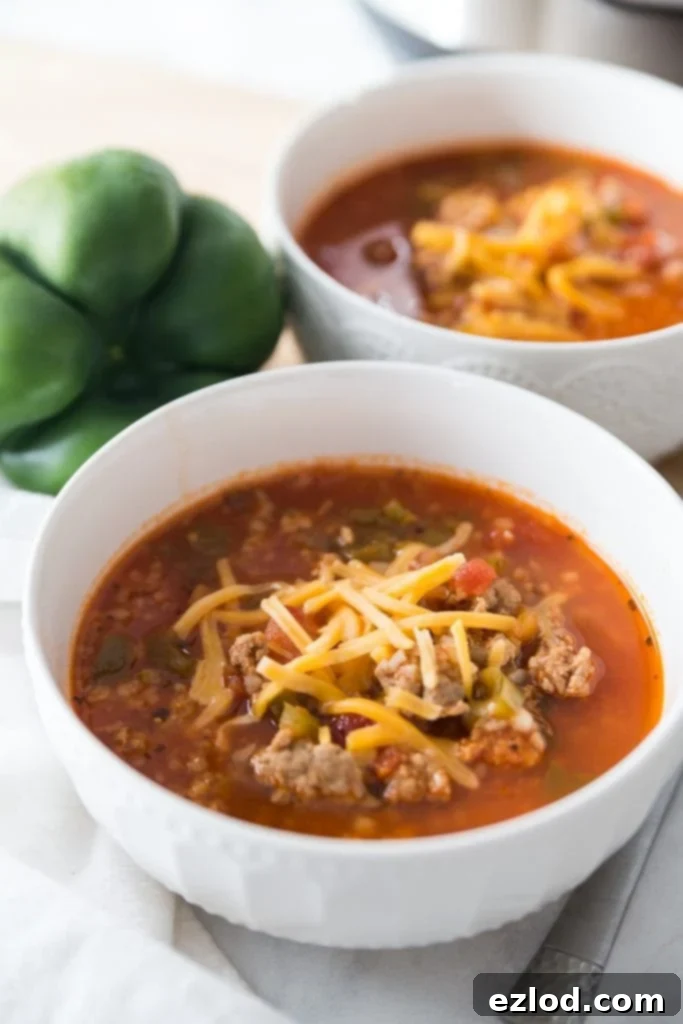 Two bowls of low carb stuffed pepper soup topped with shredded cheddar cheese, made in the Instant Pot and ready for gameday