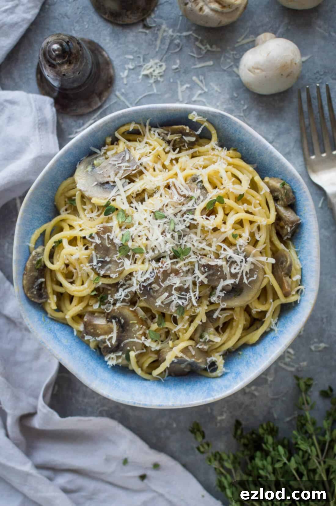 A blue bowl of vegan one pot mushroom pasta with vegan parmesan