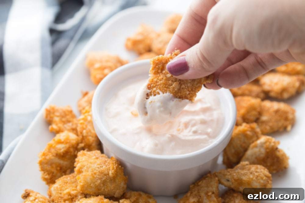 A platter of Air Fryer Buffalo Chicken Nuggets with one being dipped in buffalo blue cheese dip 