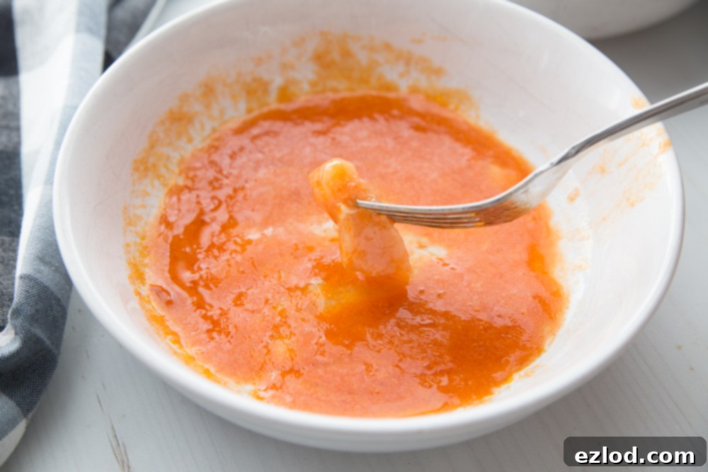Buffalo Chicken Nuggets being dipped in buffalo sauce and egg white