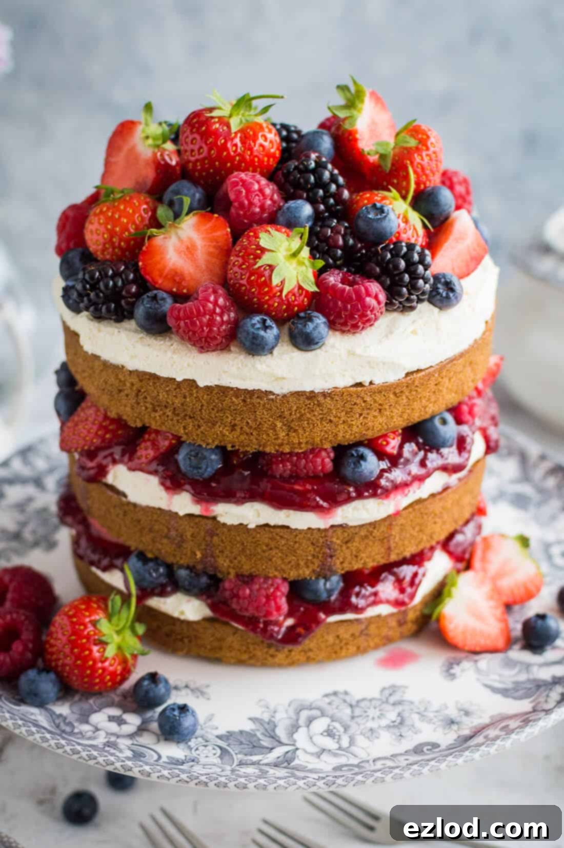 Close up of vegan vanilla cake with vanilla buttercream, raspberry jam and berries