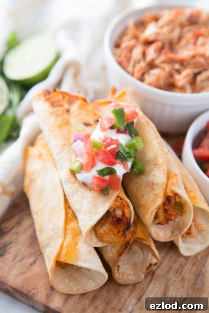 A delicious pile of Healthy Instant Pot Air Fryer Chicken Taquitos on a wooden cutting board, garnished with fresh cilantro and salsa, ready to be enjoyed as a quick and easy family dinner.