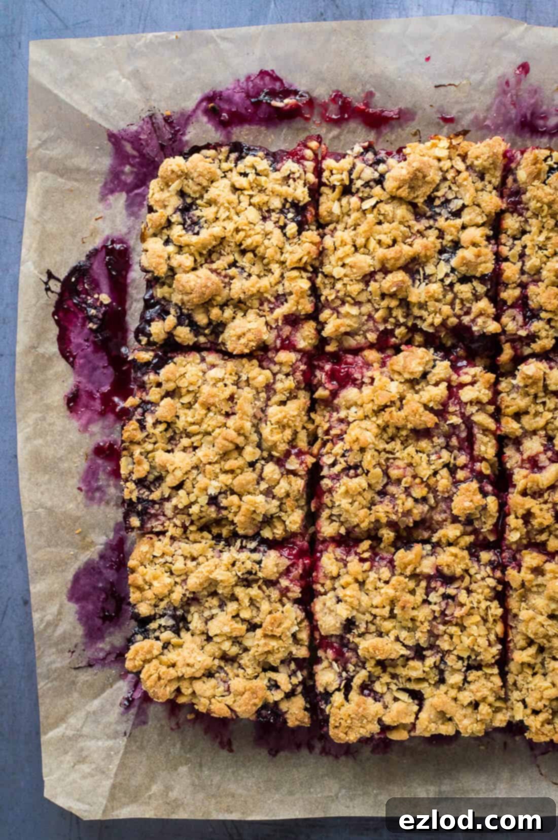 Photo of vegan berry crumble bars cut into neat squares, displaying the thick berry layer.