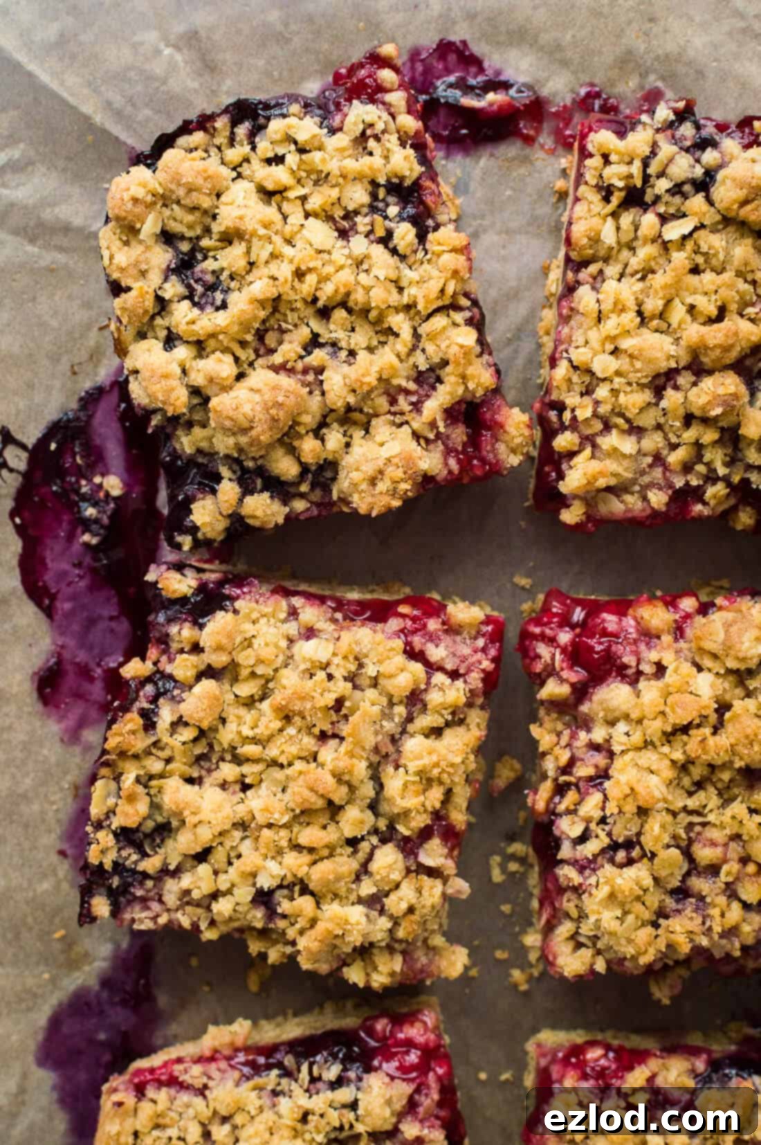 Close up shot of several squares of vegan berry crumble bars, highlighting their crumbly texture and vibrant berry filling.