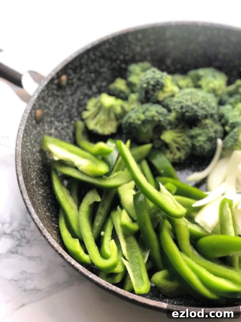 A colorful array of chopped bell peppers, fresh broccoli florets, and sliced onions sizzling in a hot skillet, ready to be incorporated into a delicious stir fry.