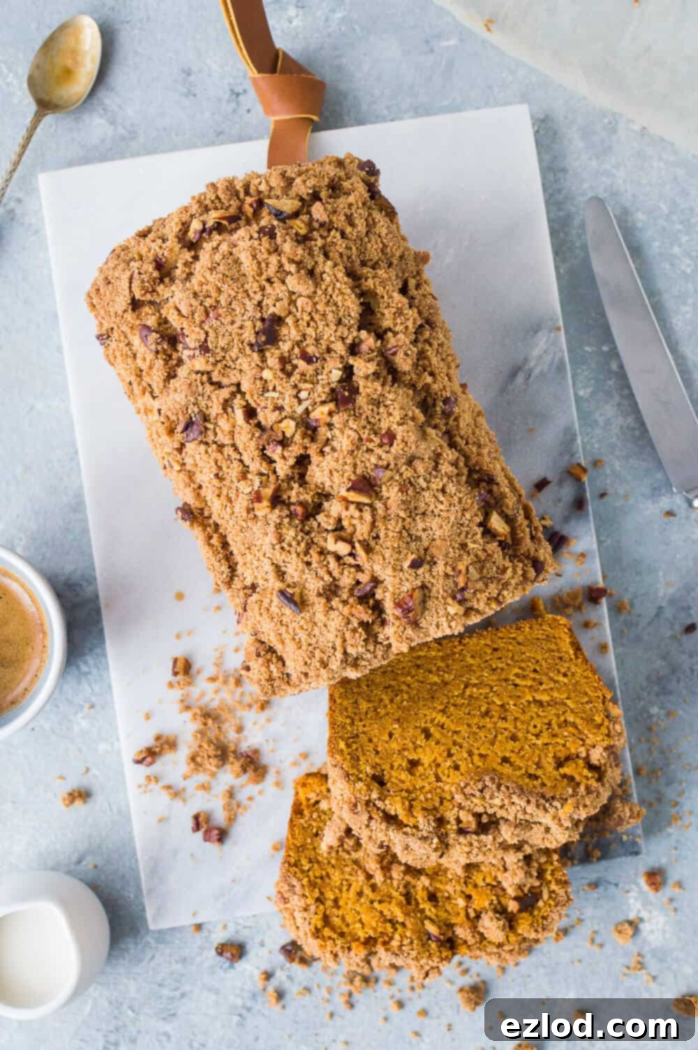 A beautiful loaf of vegan sweet potato bread with pecan streusel artfully arranged on a marble board, accompanied by a steaming cup of coffee.