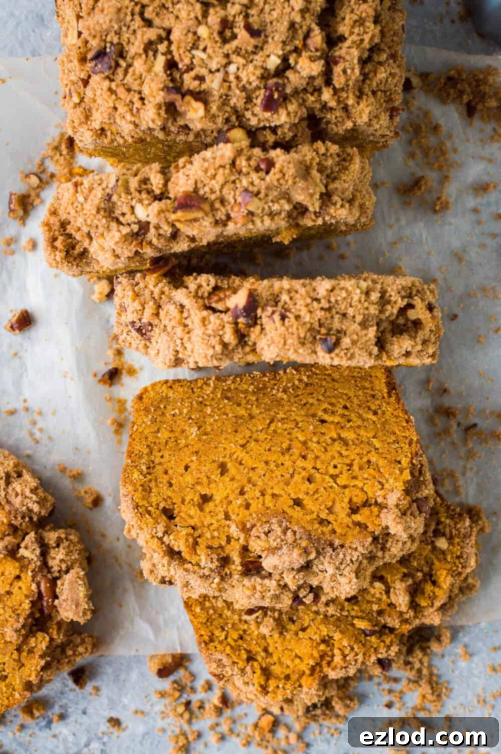 A top-down shot showcasing a whole vegan sweet potato loaf cake generously topped with crunchy pecan streusel, set against a stylish grey background.