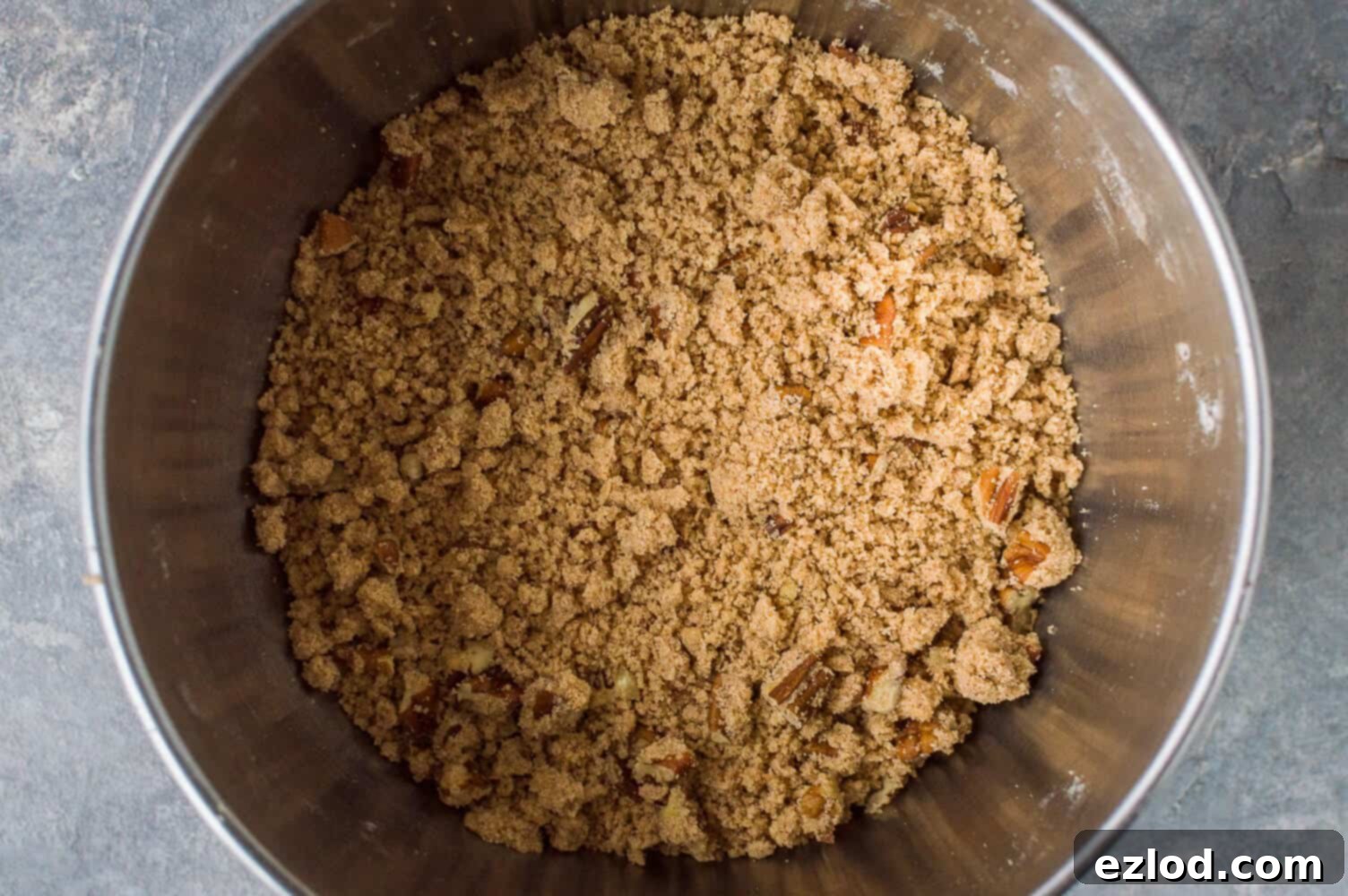 Delicious pecan streusel topping in a bowl, featuring a crumbly texture with visible chopped pecans, ready to crown the sweet potato bread.