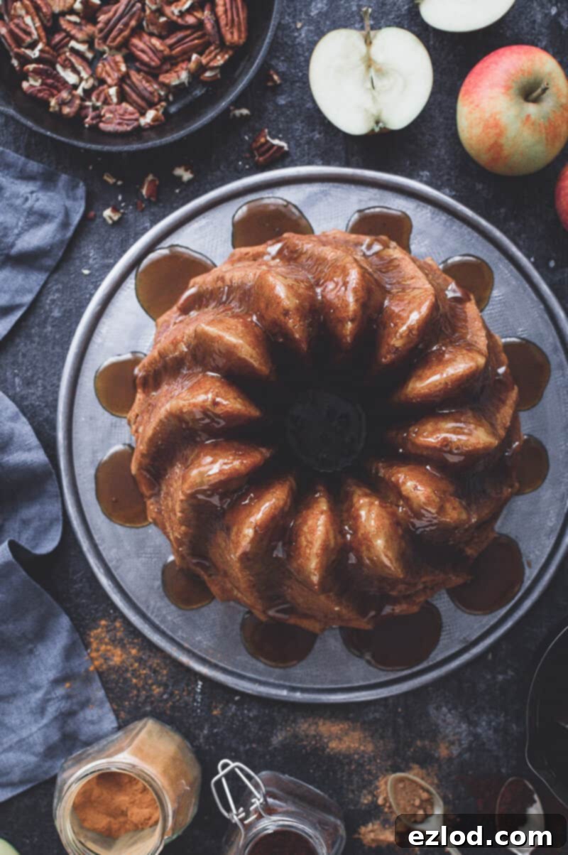 vegan apple bundt cake with coconut caramel on a dark background with apples, pecans and spices.