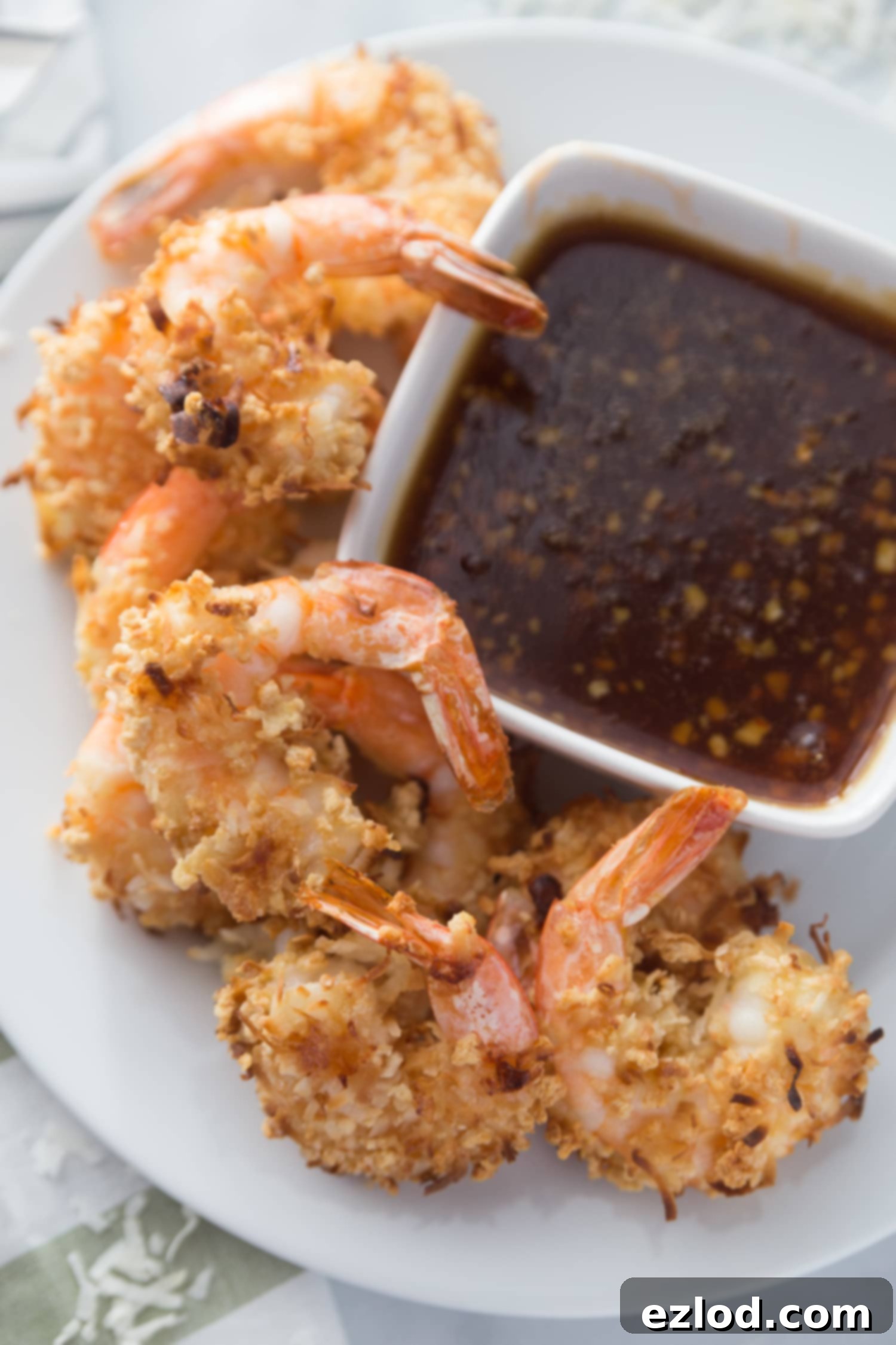 An overhead shot of several coconut shrimp sitting next to a bowl of homemade paleo sweet chili sauce