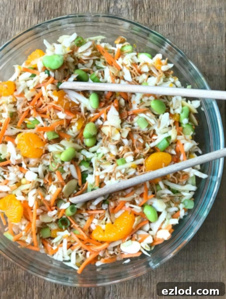 Ramen Noodle Salad in a Glass Bowl with Wooden tongs, a healthy and delicious Ultimate Portion Fix lunch option.