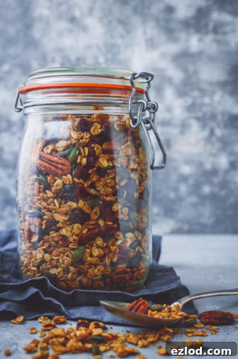 A glass jar full of pumpkin spice granola on a grey background