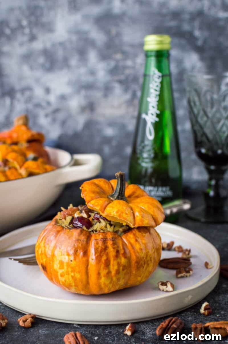 A stuffed mini pumpkin on a plate with a bottle of Appletiser and a glass in the background.