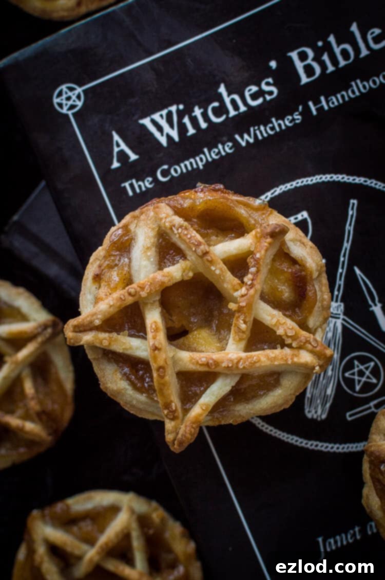 A mini, pentagram topped vegan apple pie on top of a witches' bible book.