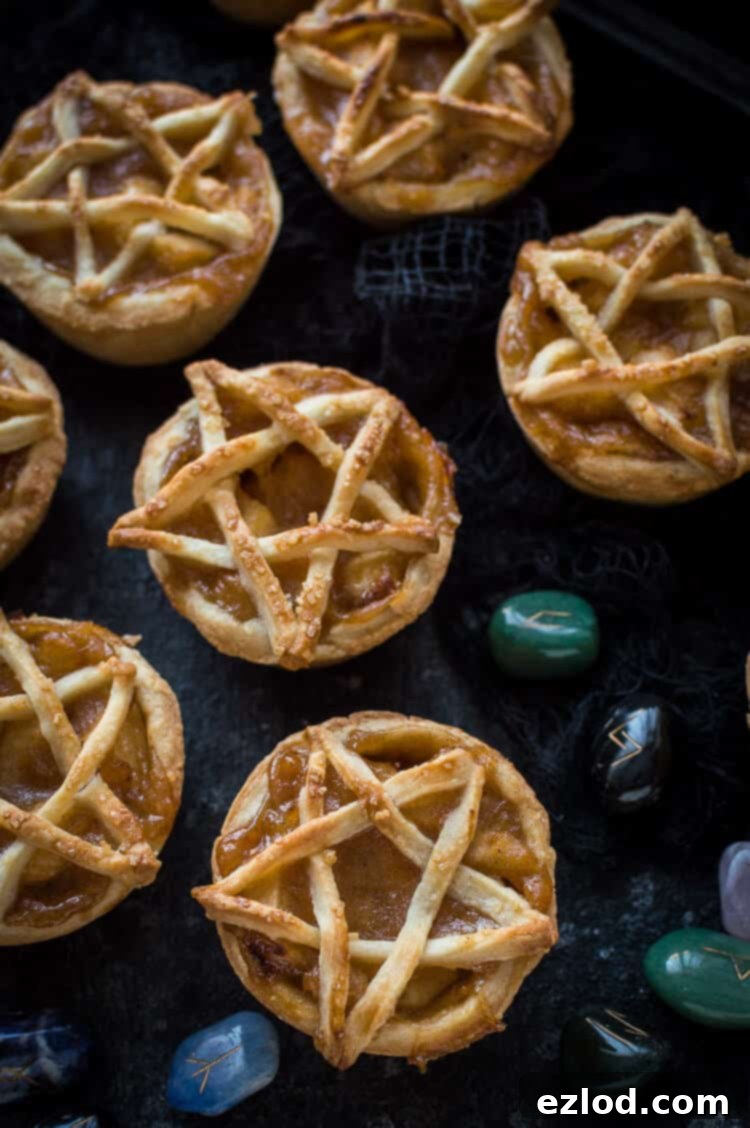 Mini pentagram topped vegan apple pies on a black background with runestones.