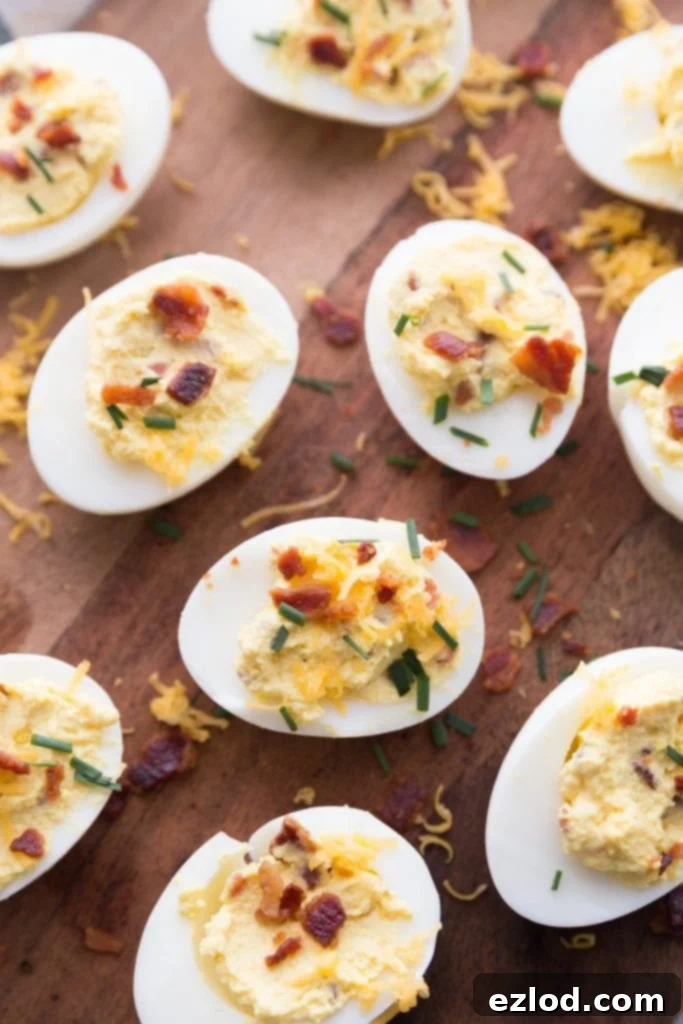 Close-up of Instant Pot Deviled Eggs with bacon, cheddar, and chive garnish on a white platter