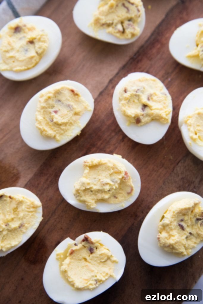 A close-up of a single Instant Pot Deviled Egg, showcasing the rich filling and toppings on a rustic background
