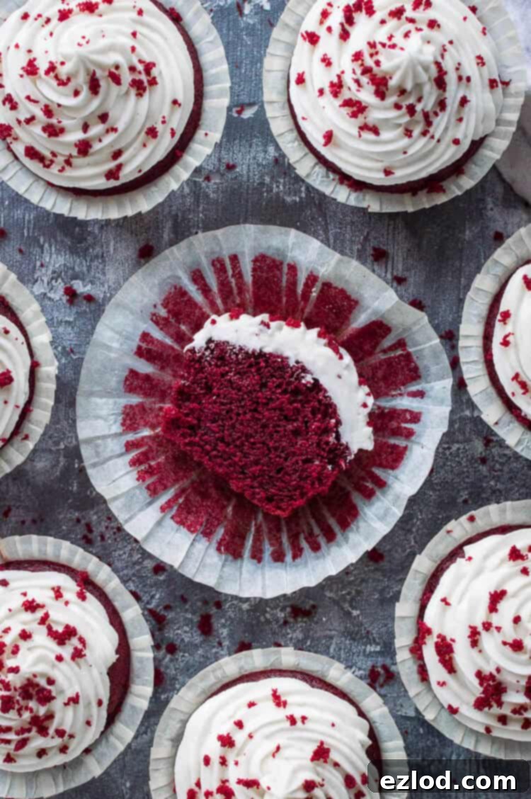 Top down shot of vegan red velvet cupcakes with cream cheese frosting with one sliced in half.