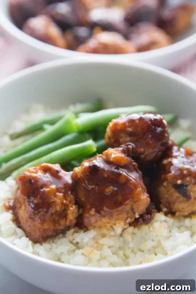 A close up shot of Asian Chicken Meatballs over a bowl of cauli rice