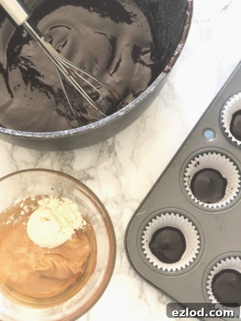 A cupcake tin, peanut butter, and a saucepan of homemade chocolate ready to make peanut butter cups 