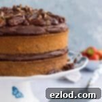 Side shot of vegan maple pecan cake with chocolate cashew cream frosting and maple pecans on a blue and white cake stand.